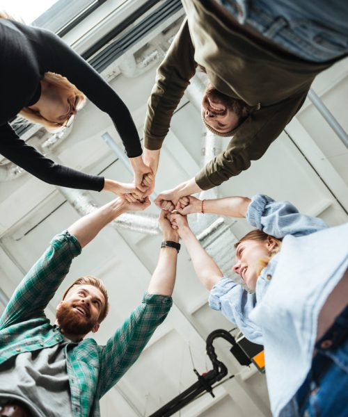Colleagues in office holding hands of each other Image of young colleagues in office holding hands of each other. Looking aside.